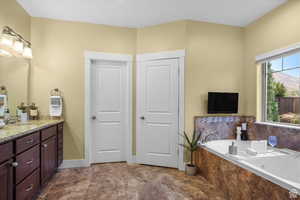 Full bathroom with vanity, baseboards, and a bath