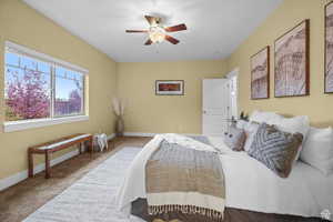 Bedroom with light carpet, ceiling fan, and baseboards