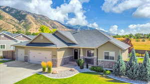 Craftsman-style house featuring stone siding, a mountain view, an attached garage, and concrete driveway