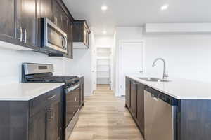 Kitchen featuring light wood-style flooring, recessed lighting, a sink, light countertops, and appliances with stainless steel finishes