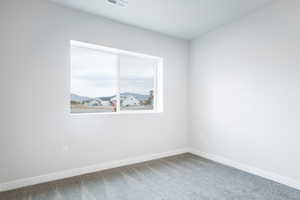 Unfurnished room featuring carpet floors, visible vents, and baseboards