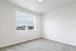 Carpeted spare room featuring visible vents and baseboards