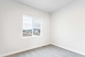 Carpeted empty room featuring visible vents, a mountain view, and baseboards