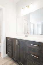 Bathroom featuring a stall shower, vanity, toilet, and wood finished floors