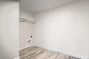 Laundry area featuring light wood-type flooring, laundry area, baseboards, and electric dryer hookup