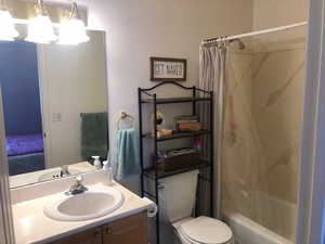 Bathroom featuring toilet, shower / tub combo,  and vanity