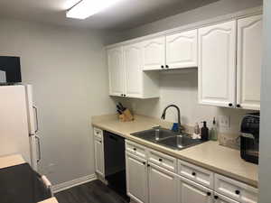 Kitchen with dishwasher, light countertops, a sink, and white cabinetry