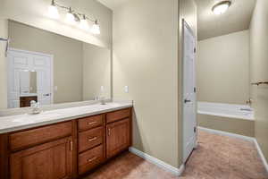 Full bath featuring a garden tub, a sink, baseboards, and double vanity