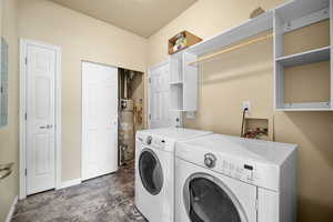 Washroom featuring gas water heater, washing machine and clothes dryer, a textured ceiling, laundry area, and baseboards