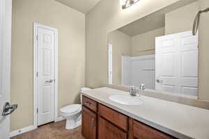 Full bath featuring toilet, walk in shower, vanity, and baseboards