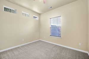 Spare room with carpet, visible vents, ceiling fan, and baseboards