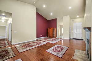 Interior space with visible vents, wood finished floors, high vaulted ceiling, a tile fireplace, and baseboards