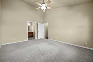 Unfurnished bedroom featuring carpet floors, ensuite bath, a high ceiling, and baseboards