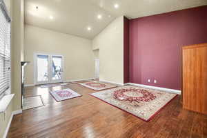 Interior space featuring high vaulted ceiling, french doors, baseboards, and wood finished floors