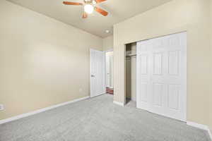 Unfurnished bedroom with light carpet, a ceiling fan, baseboards, and a closet