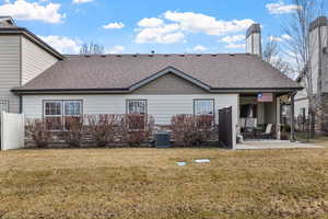 Back of property featuring a patio, roof with shingles, fence, and a lawn