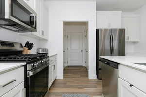 Kitchen featuring white cabinetry, stainless steel appliances, and hardwood / wood-style flooring