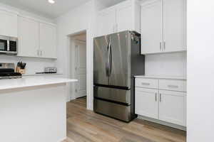 Kitchen featuring white cabinets, wood-type flooring, appliances with stainless steel finishes, and backsplash