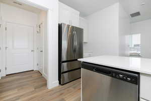 Kitchen featuring white cabinetry, wood-type flooring, and stainless steel appliances