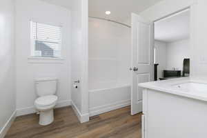 Primary bathroom featuring toilet, vanity, shower / tub combination, and wood-type flooring