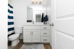 Bathroom with toilet, wood-type flooring, and vanity