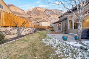 View of fenced backyard, a mountain view, and a patio & walk out deck