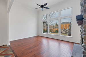 Empty room featuring arched walkways, dark wood-type flooring, baseboards, and a healthy amount of sunlight