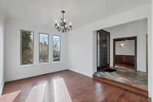 Formal dining room featuring visible vents, baseboards, ornamental molding, dark wood finished floors, and an inviting chandelier