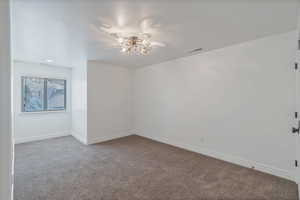 Bedroom with a chandelier, visible vents, light carpet, and baseboards