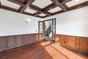 Main Floor office with coffered ceiling, beam ceiling, a wainscoted wall, and dark wood-style flooring