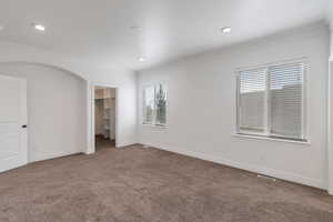 Primary bedroom with carpet floors, baseboards, arched walkways, and ornamental molding