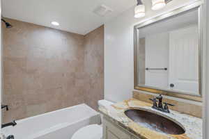 Full bath with toilet, bathing tub / shower combination, visible vents, and vanity with copper sink.