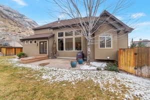 Fenced back yard, walk out deck to a large concrete patio area, gas BBQ, a mountain view, a lawn, and stucco siding