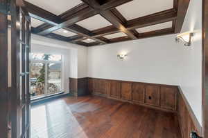 Main floor office with a wainscoted wall, coffered ceiling, and beam ceiling