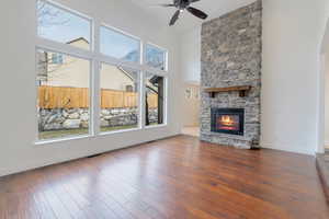 Unfurnished living room featuring arched walkways, a fireplace, a towering ceiling, baseboards, and dark wood finished floors