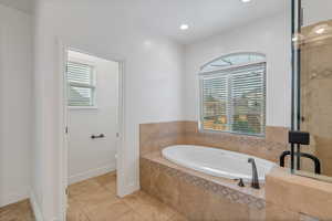 Primary bathroom featuring tile patterned flooring, a garden tub, plenty of natural light, and toilet