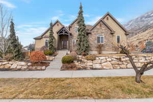 View of front facade with stone siding, a front yard, a mountain view, and stucco siding