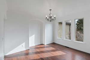 Formal Dining room with arched walkways, a wealth of natural light, wood finished floors, and visible vents