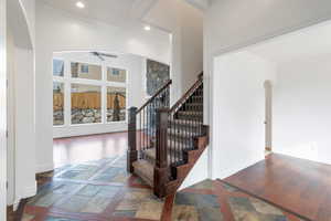 Stairway featuring a ceiling fan, arched walkways, stone & wood finished floors, and ornamental molding