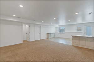 Unfurnished living room with recessed lighting, visible vents, baseboards, and light colored carpet