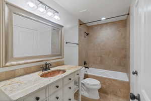 Bathroom featuring visible vents, toilet, tiled shower / bath combo, tile patterned flooring, and vanity with copper sink.