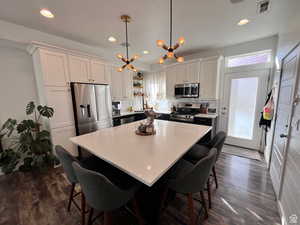 Kitchen with open shelves, stainless steel appliances, light countertops, hanging light fixtures, and white cabinetry