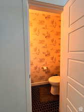 Bathroom featuring tile patterned flooring, baseboards, toilet, and wallpapered walls