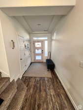 Entryway featuring baseboards, stairway, dark wood finished floors, and a raised ceiling