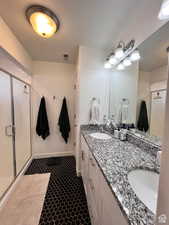 Full bath featuring double vanity, a shower stall, visible vents, and a sink