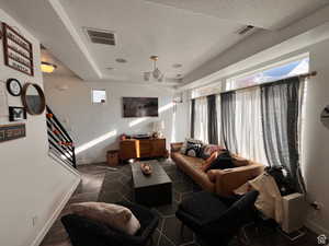 Living room featuring visible vents, plenty of natural light, and a textured ceiling