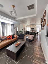 Living room with baseboards, visible vents, dark wood finished floors, and a textured ceiling