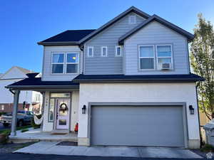 View of front of property with stucco siding, concrete driveway, covered porch, an attached garage, and cooling unit