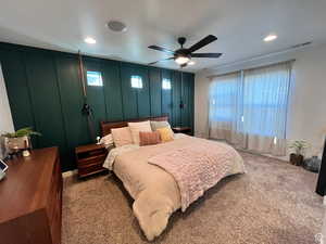 Bedroom featuring visible vents, a ceiling fan, dark colored carpet, a textured ceiling, and a decorative wall