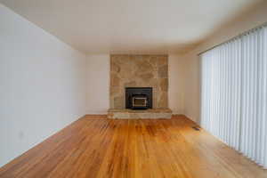 Unfurnished living room with visible vents, a wood stove, and light wood-style flooring